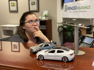 A picture of an agent pondering full coverage for a toy Delorean and Tesla